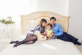 Family, parenthood and children concept - Happy mother, father and son playing together with teddy bear on bed in Royalty Free Stock Photo