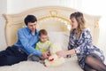 Family, parenthood and children concept - Happy mother, father and son playing together with teddy bear on bed in Royalty Free Stock Photo