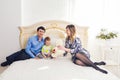 Family, parenthood and children concept - Portrait of happy mother, father and son sitting together on bed in bedroom at Royalty Free Stock Photo