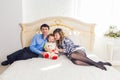 Family, parenthood and children concept - Portrait of happy mother, father and son sitting together on bed in bedroom at Royalty Free Stock Photo