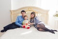 Family, parenthood and children concept - Portrait of happy mother, father and son sitting together on bed in bedroom at Royalty Free Stock Photo