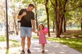 Family, parenthood, fatherhood, adoption and people concept - happy father and little girl walking holding in hand in