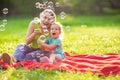 Family in park -Female child blows soup foam and make bubbles wi Royalty Free Stock Photo