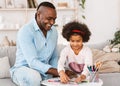 Family pastimes. African American grandfather and his lovely granddaughter drawing together at home Royalty Free Stock Photo