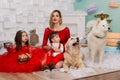 Family photo portrait. Mom and her two children and two white dogs in red clothes celebrate the Chistmas, new year