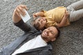 Family photo. Young cheerful father making selfie with his little son, both smiling to smartphone camera, lying on floor Royalty Free Stock Photo