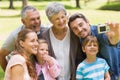 Family photographing themselves with digital camera in park Royalty Free Stock Photo