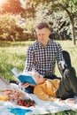 Family picnic. Dad and son in a green garden in sunny weather on a picnic eating pizza and reading book Royalty Free Stock Photo