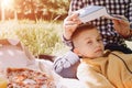 Family picnic. Dad and son in a green garden in sunny weather on a picnic eating pizza and reading book Royalty Free Stock Photo