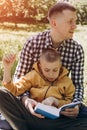 Family picnic. Dad and son in a green garden in sunny weather on a picnic eating pizza and reading book Royalty Free Stock Photo