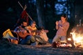 Family camping in the woods; Spring or autumn camping with campfire at night ; camping, travel, tourism, hike and people concept. Royalty Free Stock Photo