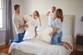 Family pillow fight, in parents bedroom and kids smile with happiness. Children jump on a bed, playing with mom and dad Royalty Free Stock Photo