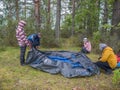 Family pitch a tent in the forest. Ecotourism, visiting fragile, pristine, undisturbed natural areas. Active holidays in Karelia