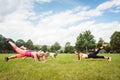 Family planking outdoors in meadow with fitness teacher