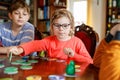 Family playing board game at home. Kids play strategic game. Little sister girl and two school brothers boys. Fun indoor Royalty Free Stock Photo