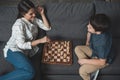 Young woman making a move in chess game while playing with her son on couch Royalty Free Stock Photo