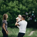Family playing outdoors, blowing soap bubbles. Royalty Free Stock Photo