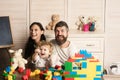 Family playing with plastic blocks and plush toys.