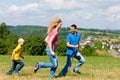 Family playing tag on meadow in summer Royalty Free Stock Photo