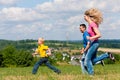 Family playing tag on meadow in summer Royalty Free Stock Photo