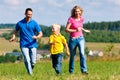 Family playing tag on meadow in summer Royalty Free Stock Photo