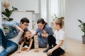 Family playing tower building game watching in excitment, waiting for it to fall Royalty Free Stock Photo