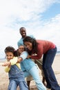 Family playing tug of war on beach Royalty Free Stock Photo