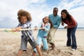 Family playing tug of war on beach Royalty Free Stock Photo