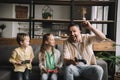 Family playing video game with joysticks while father showing winner gesture. Royalty Free Stock Photo