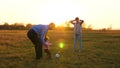 Family playing with younger baby with soccer ball in the park at sunset. Happy dad and child kick ball. happy family Royalty Free Stock Photo