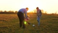 Family playing with younger baby with soccer ball in the park at sunset. Happy dad and child kick ball. happy family Royalty Free Stock Photo