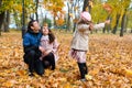 Family portrait in an autumn park. Happy people playing with fallen yellow leaves Royalty Free Stock Photo