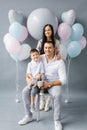 Family portrait with balloons in the studio on a gray background. Birthday Royalty Free Stock Photo