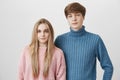 Family portrait of caucasian young couple in sweaters. Fair-haired boy and girl with blue eyes look with calm and Royalty Free Stock Photo