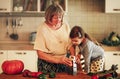 Family portrait of grandmother and granddaughter cooking together in kitchen at home