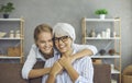 Portrait of happy mature lady together with her daughter or granddaughter at home