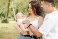 Family portrait. Happy parents admire their laughing baby in mom& x27;s arms on summer on walk in park. Royalty Free Stock Photo