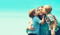 Family portrait, happy two children sons kissing their mom on a sunny day on blue sky background, Mothers day concept