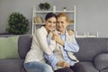 Family portrait of mature mother and her adult daughter hugging while sitting on sofa at home. Royalty Free Stock Photo