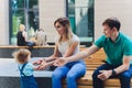 Family portrait mom and dad sitting on bench in city park with baby girl talking and smiling. Walking together at Royalty Free Stock Photo