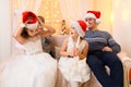 Family portrait - parent and children in home interior decorated with holiday lights and gifts, dressed in santa hat for new year