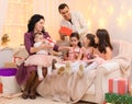 Family portrait of a parents and children, sitting on a couch in home interior decorated with lights and gifts Royalty Free Stock Photo