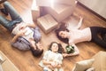 Family portrait where everybody is lying on the floor. Small girl has her teddy bear in the hnds. There is a plant near