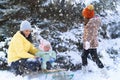 Family portrait in the winter forest, mother and children sitting and playing with snow, beautiful nature with snowy fir trees Royalty Free Stock Photo