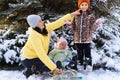 Family portrait in the winter forest, mother and children sitting and playing with snow, beautiful nature with snowy fir trees Royalty Free Stock Photo