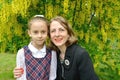 Family portrait of a woman with her first-grader daughter against the backdrop of a flowering tree