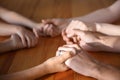 Family praying at wooden table, closeup