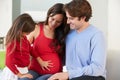 Family With Pregnant Mother Relaxing On Sofa Together