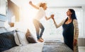 Family, pregnant woman and her son jumping on the bed while in their home together. Flare, love or smile and a boy child Royalty Free Stock Photo