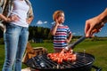 Family preparing sausages on a grill Royalty Free Stock Photo